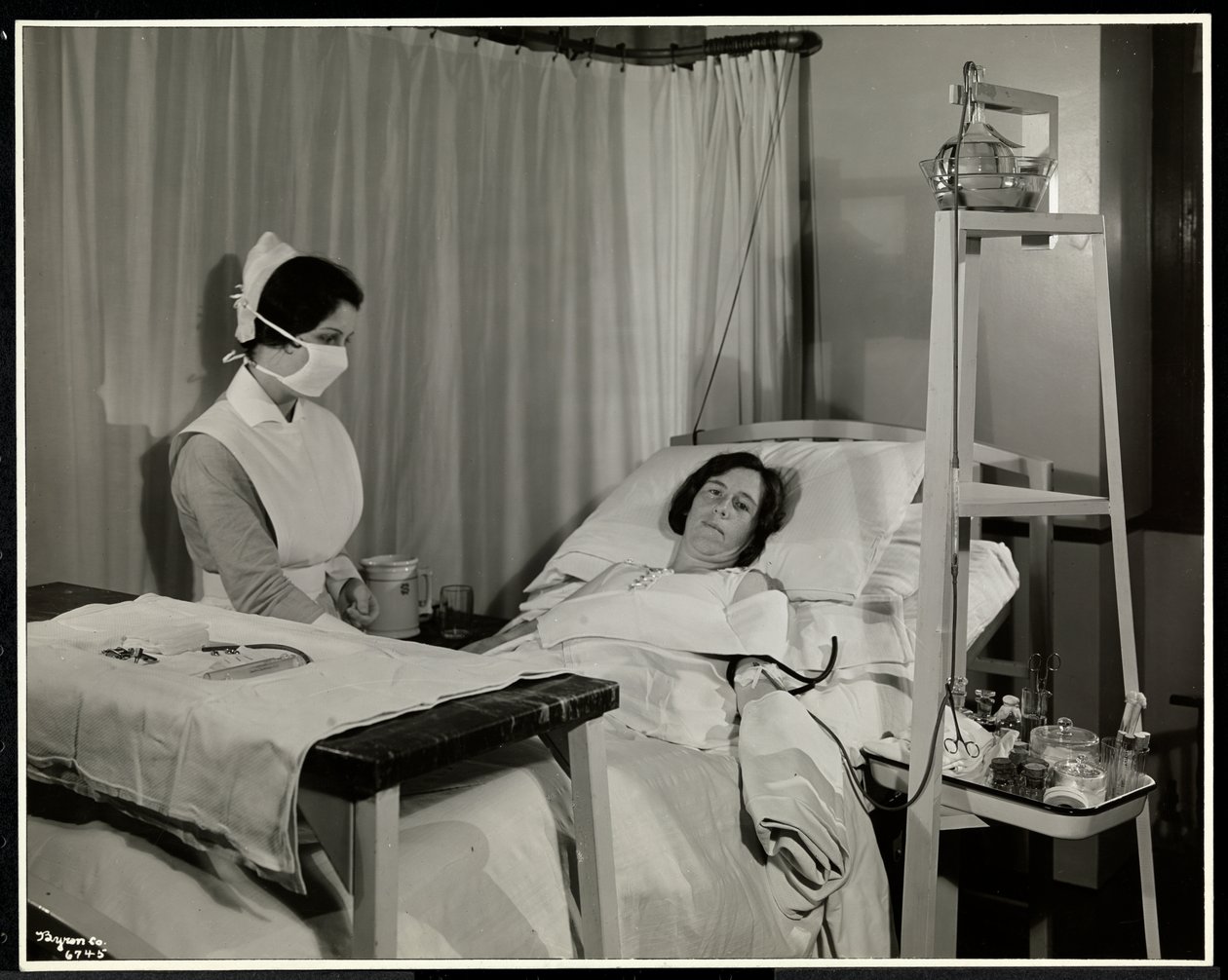 Eine maskierte Krankenschwester mit einem Patienten in einem Raum im Sloane Medical Hospital, Broadway und 168th Street, New York, 1932 von Byron Company