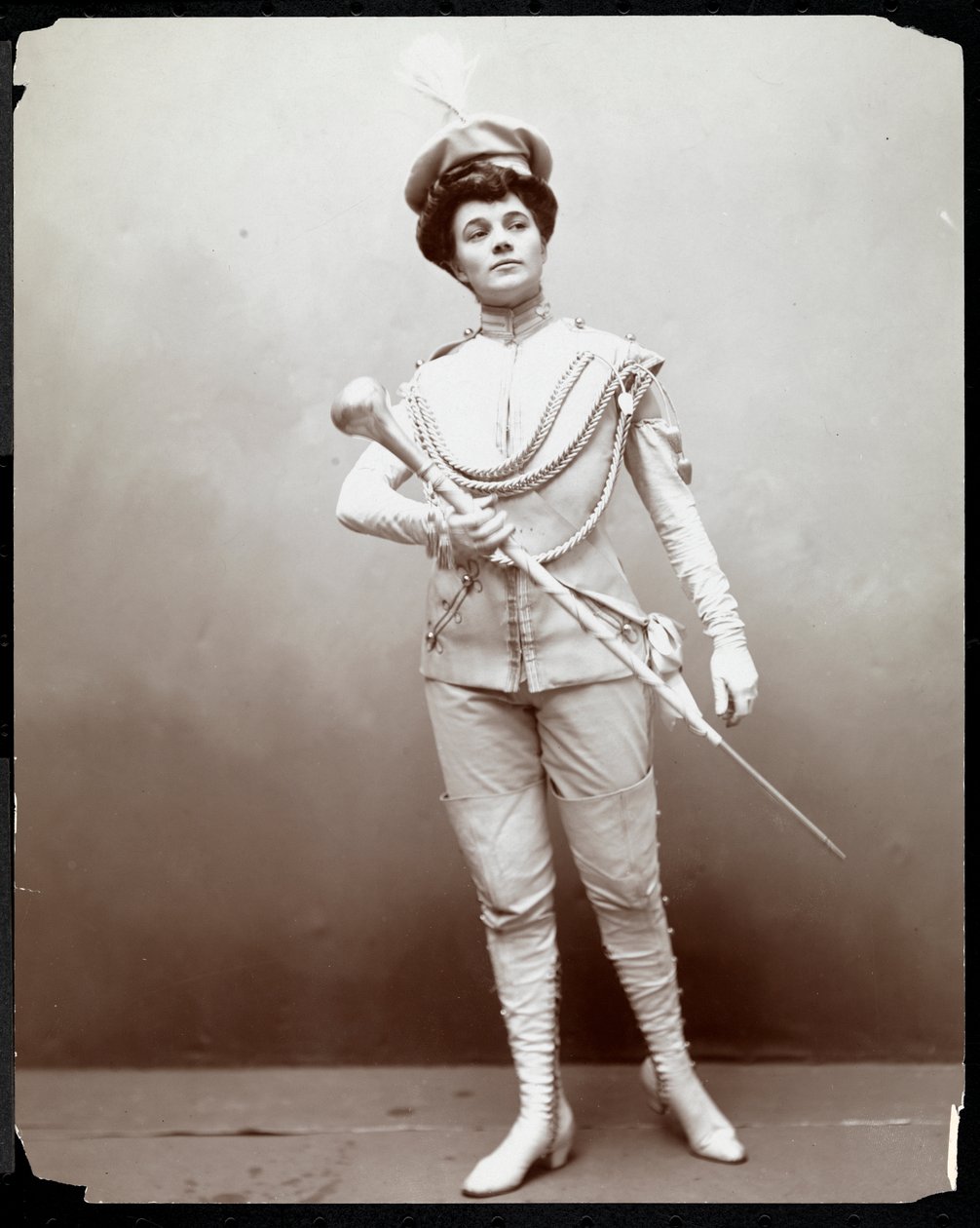 Eine Frau, die eine Banduniform modelliert und einen Taktstock hält, ca. 1898 von Byron Company
