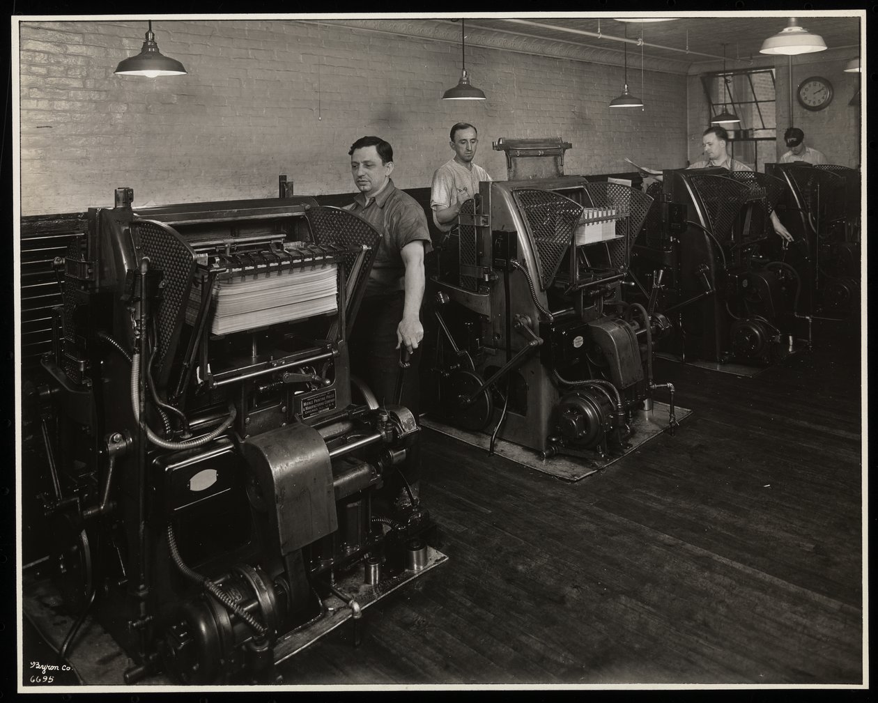 Männer arbeiten an Druckpressen bei Unz und Co., 24 Beaver Street, New York, 1932 von Byron Company