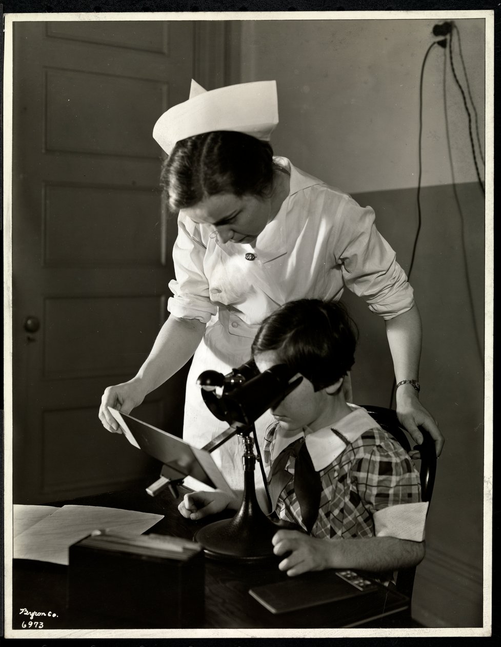 Krankenschwester und ein sehbehinderter Mädchen in der Klinik der New York Association for the Blind, 114 East 60th Street, New York, 1934 von Byron Company