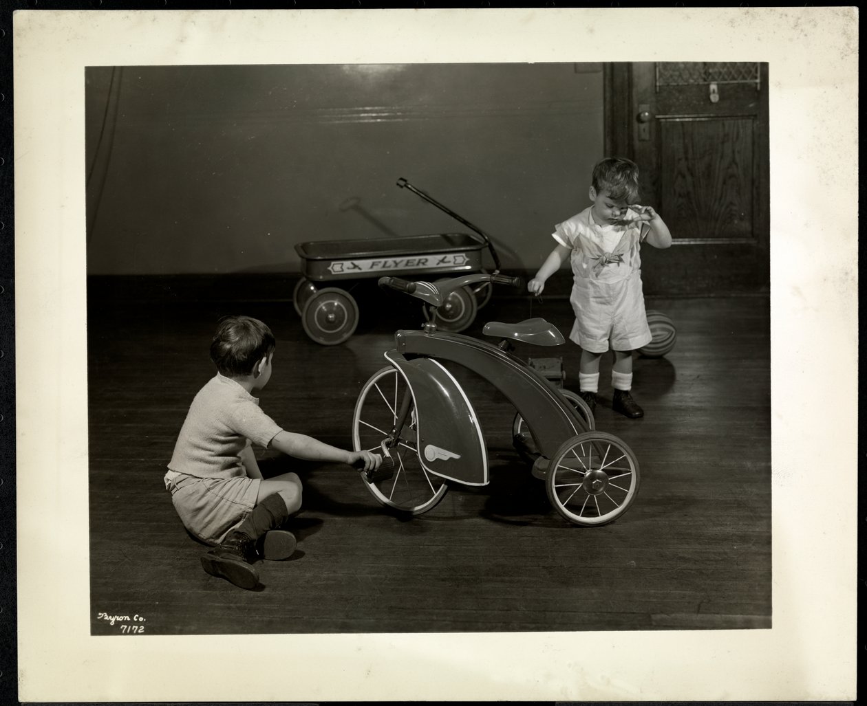 Zwei blinde Jungen spielen mit einem Dreirad und einem roten Wagen bei der New York Association for the Blind, 111 East 59th Street, New York, 1937 (Silbergelatineabzug) von Byron Company