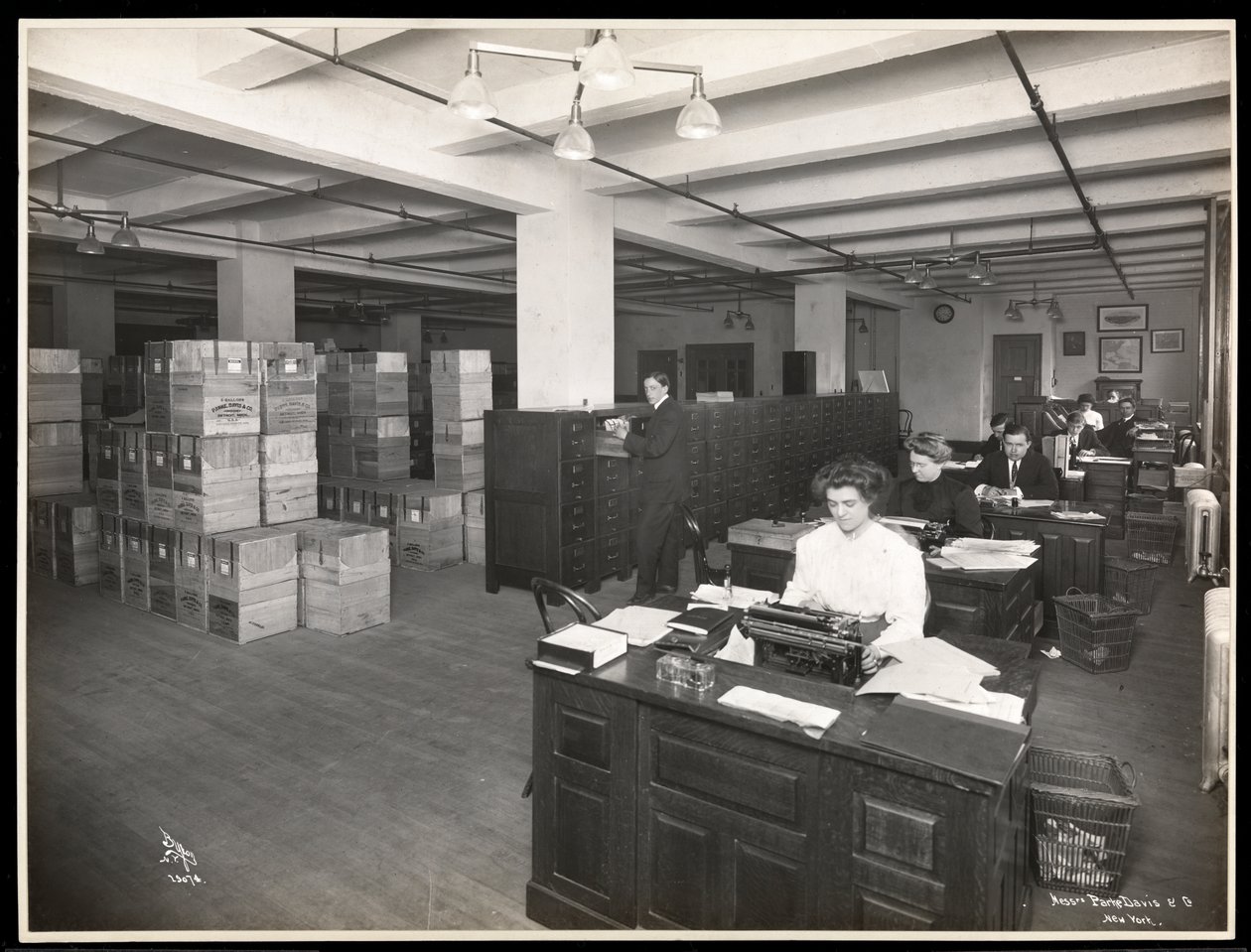 Ansicht von Männern und Frauen an Schreibtischen in einem Versandraum bei Parke, Davis und Co., Chemiker, Hudson und Vestry Streets, New York, 1910 von Byron Company