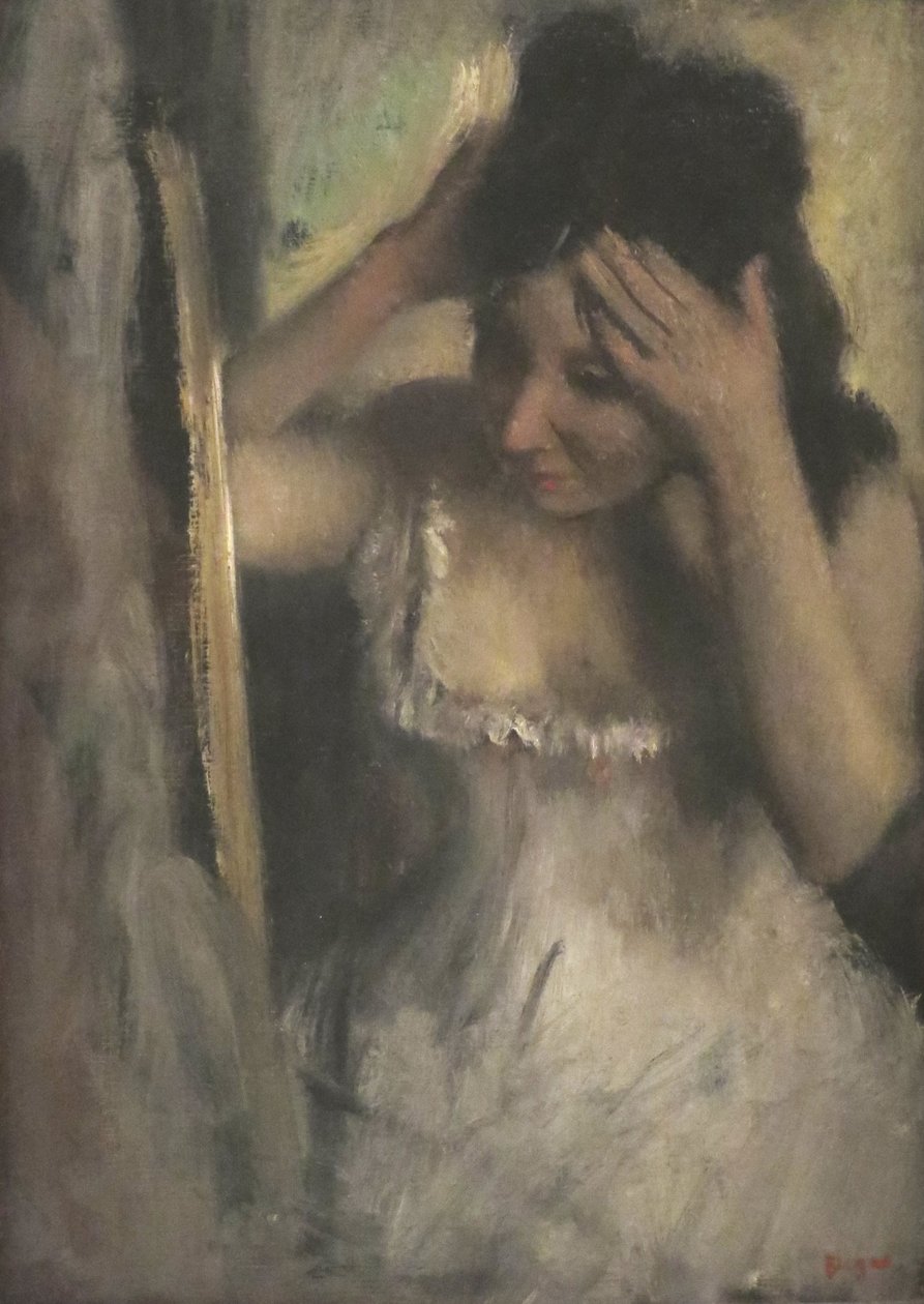 Frau kämmt ihr Haar vor einem Spiegel von Edgar Degas